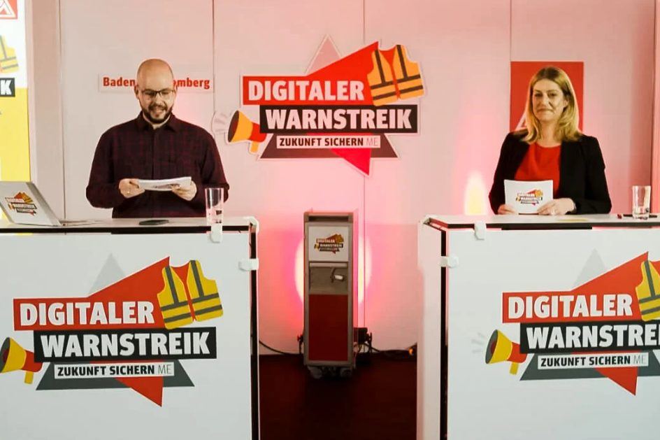 Zwei Moderierende am Pult beim Digitalen Warnstreik